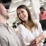A man and woman are laughing in an office.